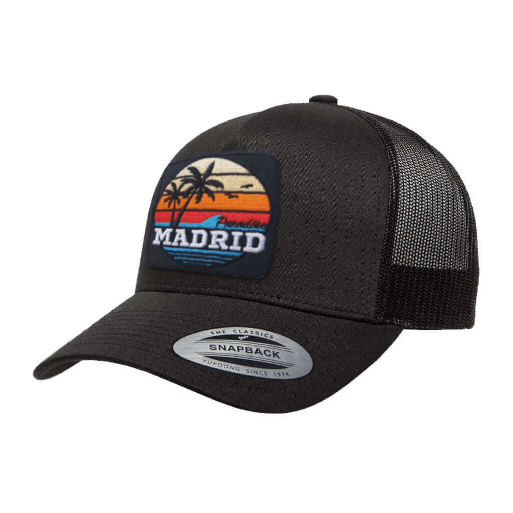 Madrid Paradise trucker cap featuring embroidered patch with palm trees and sunset design, black color.